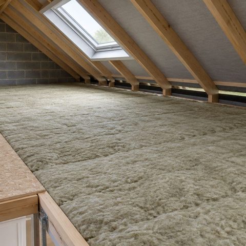 A loft insulated to full depth, with mineral wool laid across the joists and the eaves left clear for ventilation.
